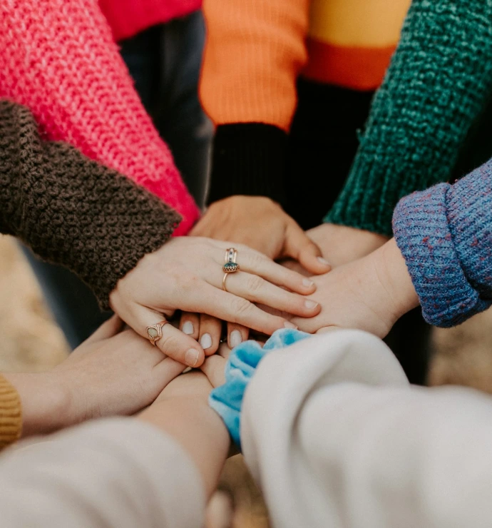 person in red sweater holding babys hand